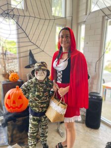 Woman in little red riding hood costume and a kid in a soldier with mask costume holding a jack o lantern