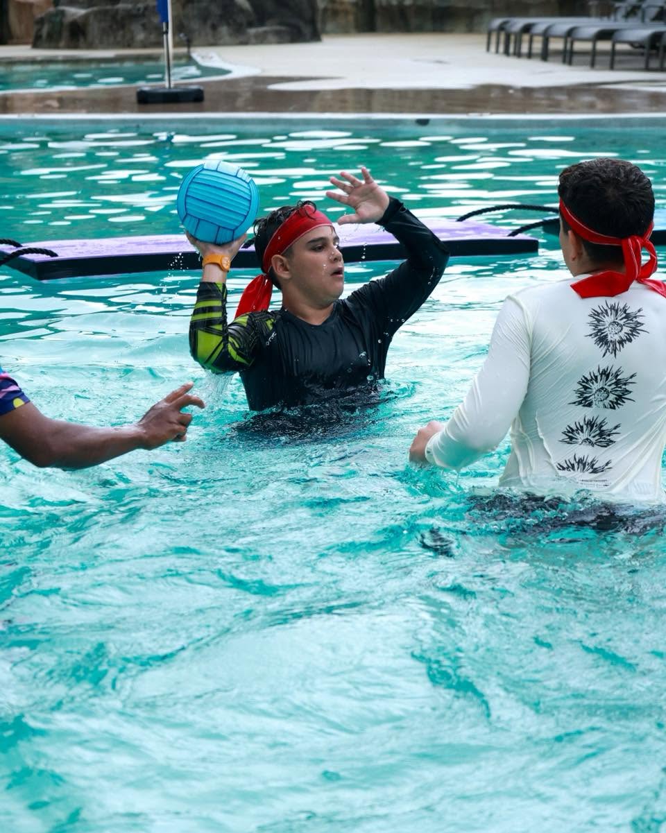 Lighthouse International School student passing the volleyball to another student in the pool